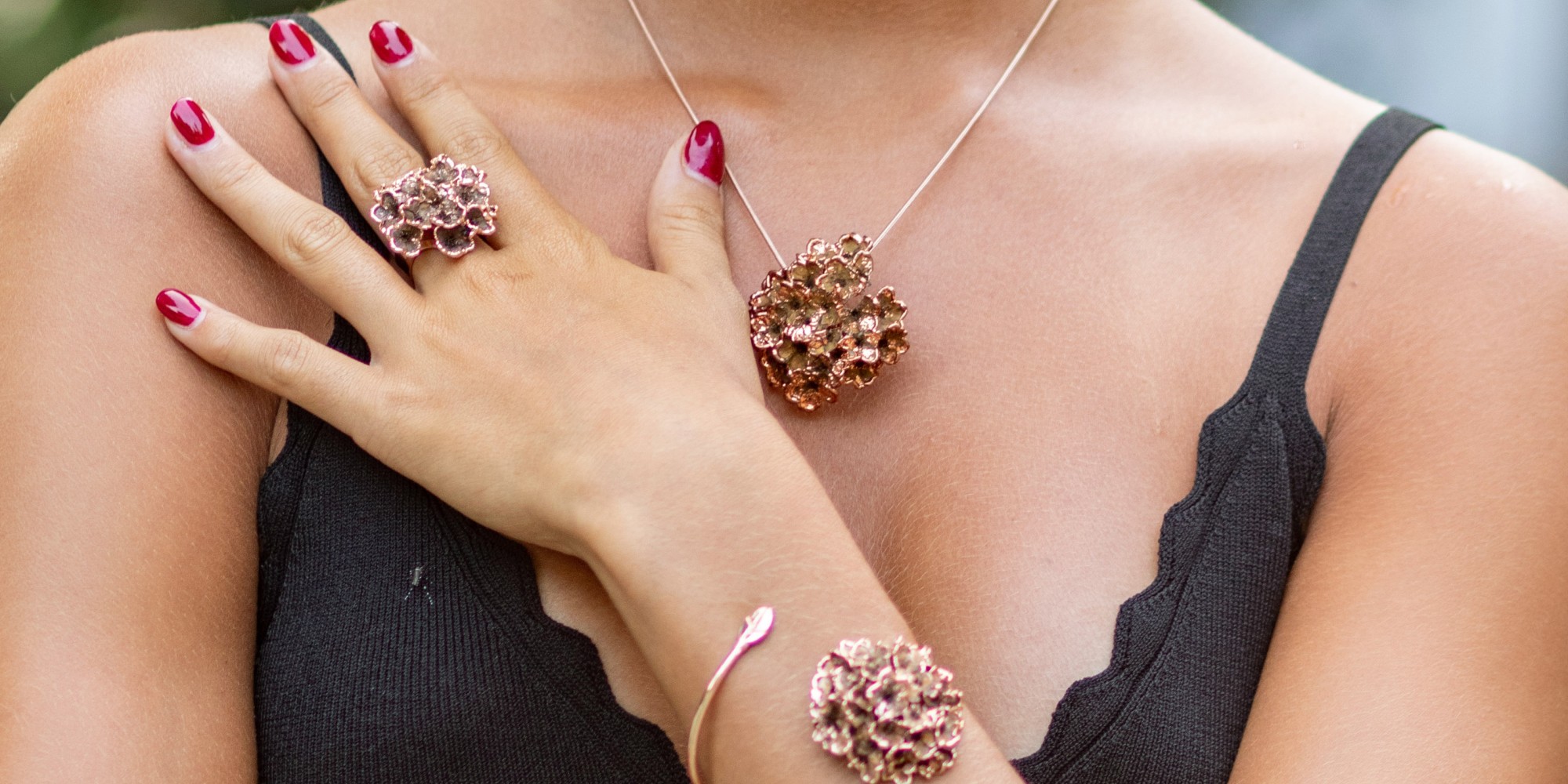 la modella indossa una parure composta da ciondolo, anello e bracciale fiori del biancospino double face; un lato naturale e l'altro placcato oro rosa