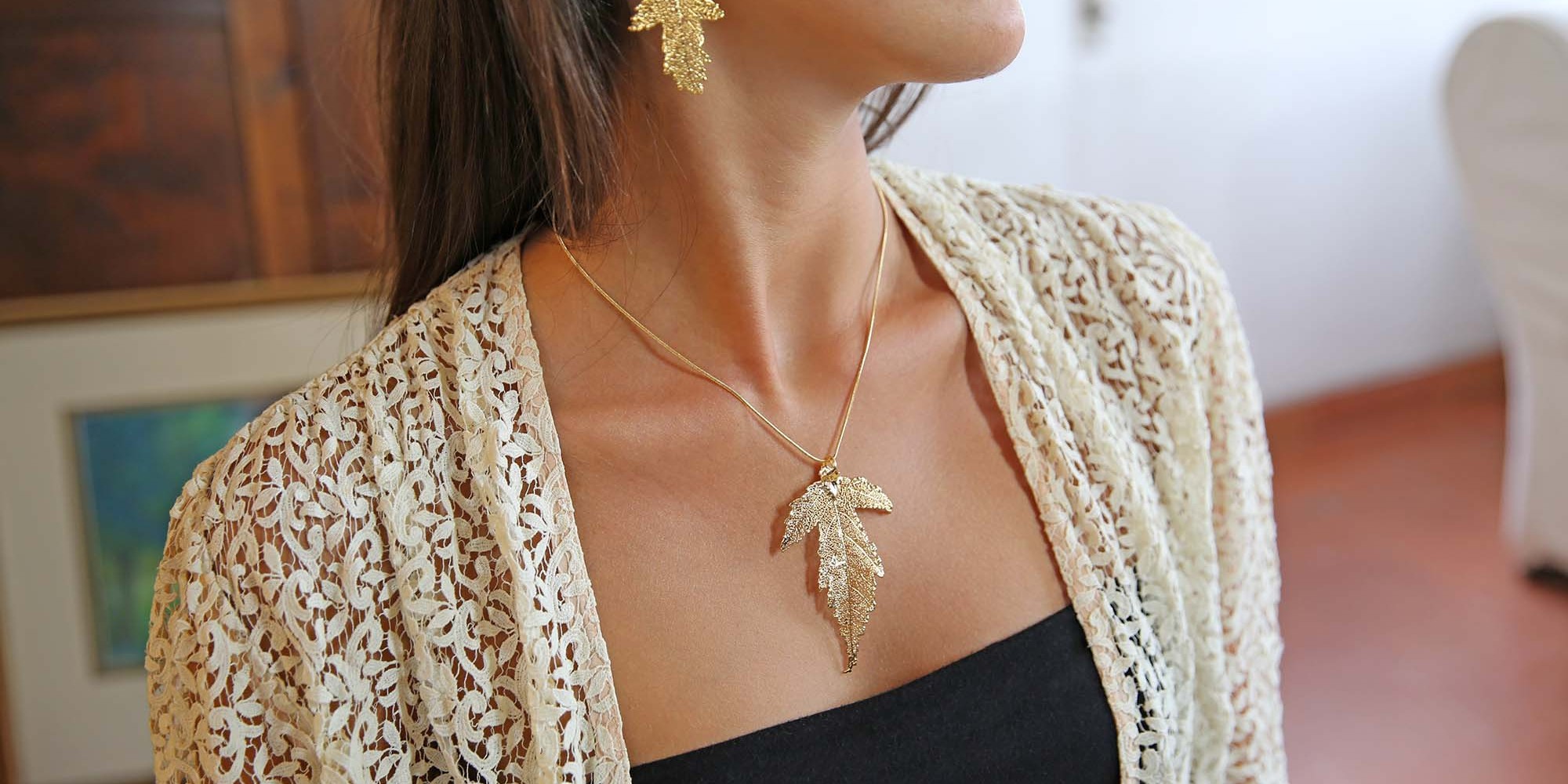 Parure indossata da modella con orecchini e ciondolo di vere foglie di gelso placcate oro