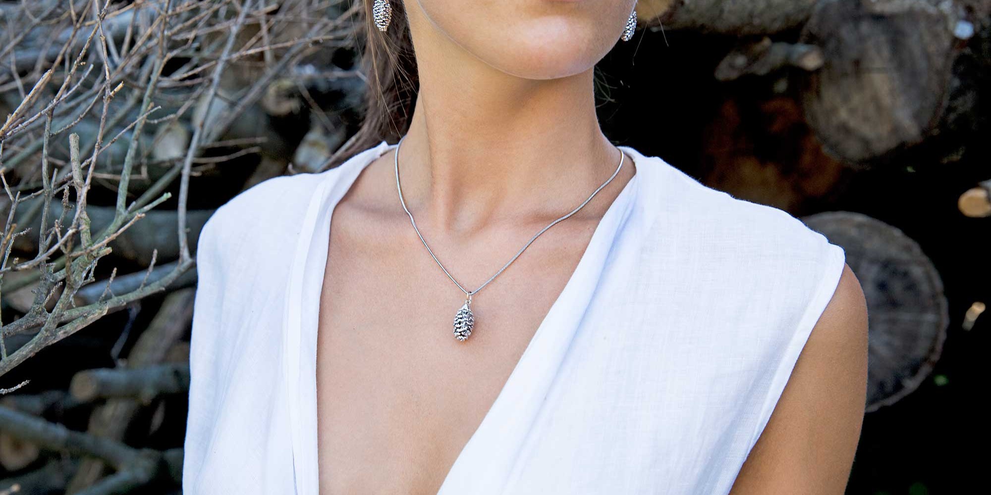 Parure indossata da modella con orecchini e ciondolo di vere pigne placcate argento