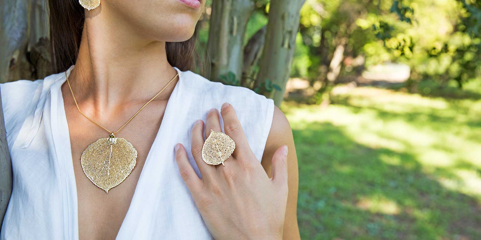 Parure indossata da modella con orecchini, ciondolo e anello di vere foglie di pioppo tremolo placcate oro