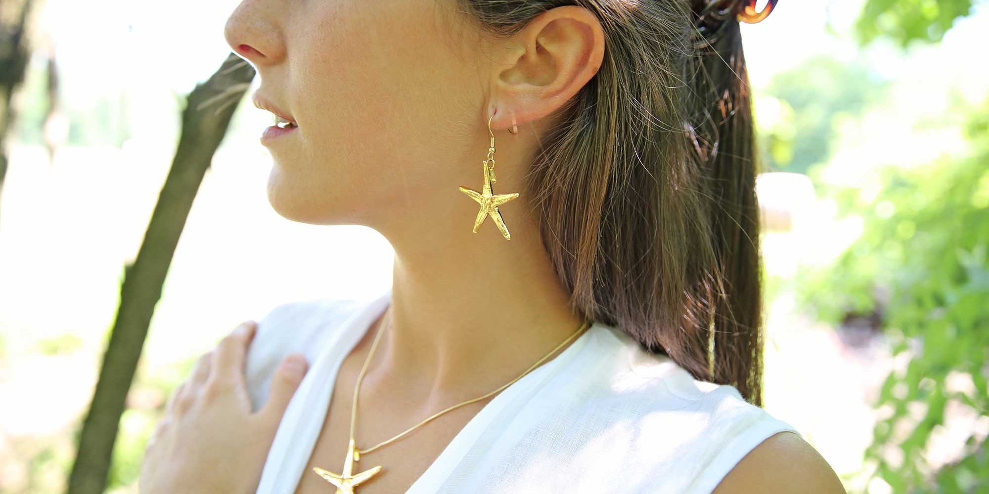 Parure indossata da modella con orecchini e ciondolo di stampi in metallo di vere stelle marine placcate oro